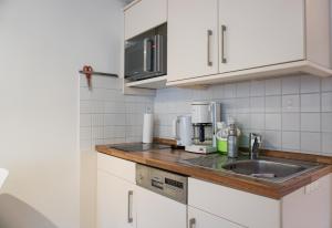 a kitchen with white cabinets and a sink at Westerhoern 46 Haus 2 App 24 in Keitum +7 photos