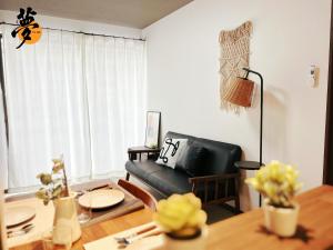 a living room with a black leather couch and a table at Yume夢 堺店 in Sakai