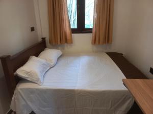 a bedroom with a bed with white sheets and a window at Calm Stay in Badulla