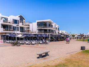 a bench in front of a building with chairs and umbrellas at 167 Eden on the Bay in Big Bay