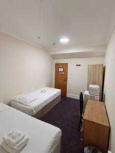 a hotel room with two beds and a desk at Ilford York Hotel in Ilford