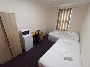 a hotel room with two beds and a microwave at Ilford York Hotel in Ilford