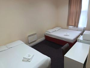 a small room with two beds and a desk at Ilford York Hotel in Ilford +5 photos