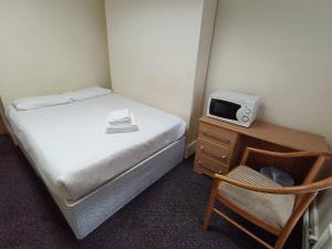 a small bedroom with a bed and a microwave at Ilford York Hotel in Ilford