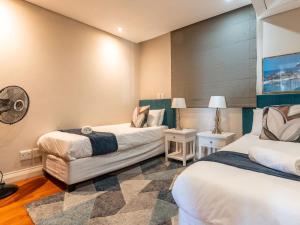 two beds in a room with two lamps at 167 Eden on the Bay in Big Bay