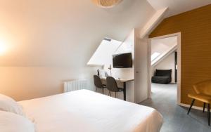a bedroom with a bed and a desk with a television at Logis Hotel Restaurant Au Chêne Vert, Saint-Brieuc in Plérin
