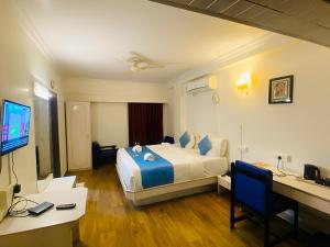 a hotel room with a bed and a desk and a computer at Hotel Crown in Ahmedabad