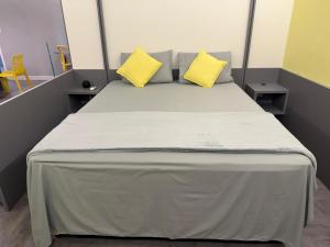 a bed in a room with two yellow pillows on it at Flat Red Sorocaba - Yellow in Sorocaba