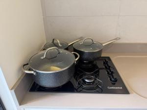 two pots on top of a stove in a kitchen at Flat Red Sorocaba - Yellow in Sorocaba +14 photos