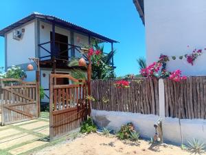 a house with a wooden fence and flowers at Villa Chalés - andar superior in Barra Grande