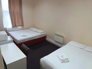 a small room with two beds and a desk at Ilford York Hotel in Ilford