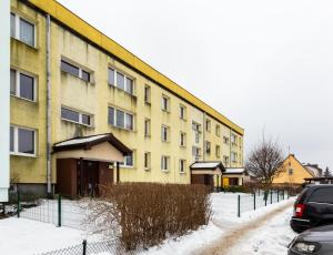 a yellow building in the snow next to a street at Reda Cozy Nest Apartment by BookingHost in Reda