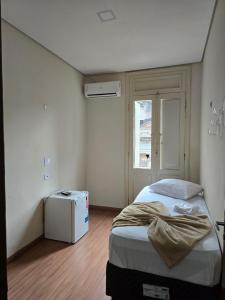 a small bedroom with a bed and a window at Hotel Santos Inn in Santos
