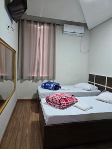 two beds in a hotel room with towels on them at Hotel Santos Inn in Santos