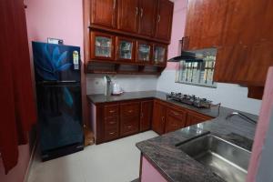 a kitchen with wooden cabinets and a black refrigerator at Greenhaven Homestay Villa in Ettumānūr