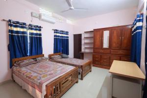 a bedroom with two beds and a dresser at Greenhaven Homestay Villa in Ettumānūr