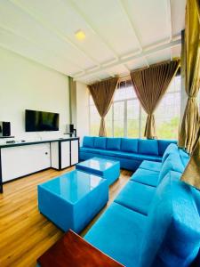 a living room with blue couches and a tv at Resolve Garden Hotel in Dodangoda