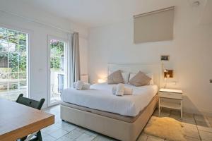 a white bedroom with a bed and a table and a window at Winahost Apartament Cirerer in Valldoreix