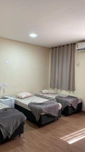 a room with three beds and a window at Hotel Santos Inn in Santos