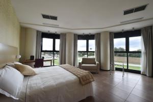 a bedroom with a bed and a chair and windows at Tatì Hotel in Lugo