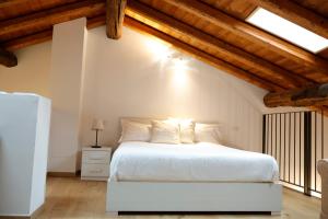 a bedroom with a white bed and wooden ceilings at Piazza del Lago Suites - Menaggio in Menaggio