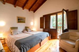 a bedroom with a bed and a chair and a window at Villa El Ñeru – Bufones de Pría, Llanes in Cuerres