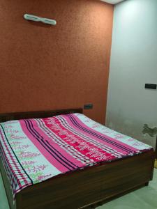 a bed with a pink and purple blanket on it at Sahib ka Ghar in Kharar