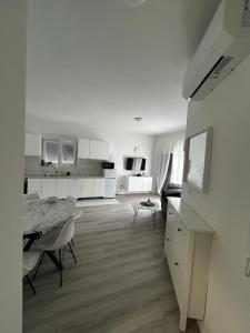 a white living room with a table and a kitchen at Monami- Apartman Mia in Vodice