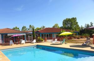 a swimming pool with chairs and umbrellas next to a house at Nid Douillet in Poncins