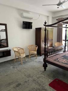 a bedroom with a bed and two chairs and a mirror at Belgi Guest House in Balapitiya