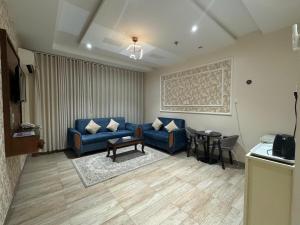 a living room with a blue couch and a table at رفاء الذهبية للشقق المخدومة - Golden Rafa Serviced Apartments Hotel in Al Makhwāh +10 photos