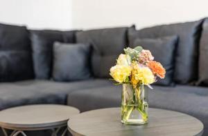 a vase of flowers on a table in front of a couch at Elbe Central Loft in Wittenberge +2 photos