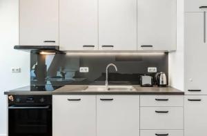 a kitchen with white cabinets and a sink at Elbe Central Loft in Wittenberge