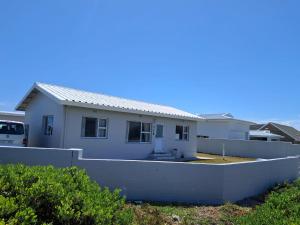 a white house behind a white wall at Haus Windhoek - Charming Coastal Escape in Struisbaai