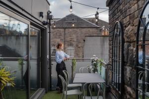 a woman standing on a balcony with a table at CODE - The Loft, Edinburgh in Edinburgh