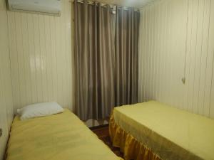 a room with two beds and a window with curtains at Um lar acolhedor in Pato Branco