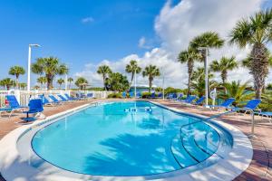 a large swimming pool with blue chairs and palm trees at ‘Emerald Dreams’ Beach & Lakefront West PCB Condo in Panama City Beach