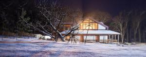 a house with a lit up window in the snow at Penates Aparthotel in Koropovo