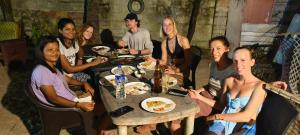 a group of people sitting around a table eating food at Funky Art Beach House in Alleppey