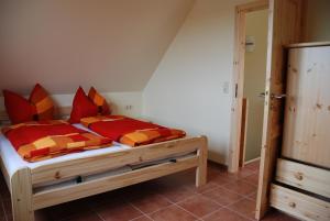 Schlafzimmer mit einem Holzbett mit roten und orangefarbenen Kissen in der Unterkunft Ferienhaus Klaus und Walter in Mechelsdorf