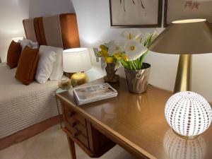 a bedroom with a table with a lamp and flowers on it at Dimora Lùmina in Gallipoli