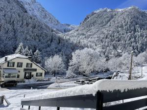 a snow covered mountain with a house and cars parked in front at Le Refuge de l'Isard in Bagnères-de-Bigorre