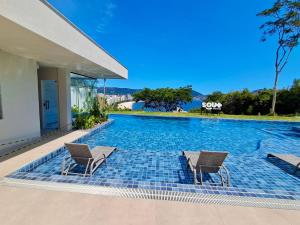 a swimming pool with two chairs in front of a house at Loft Próximo à Praia de Icaraí in Niterói