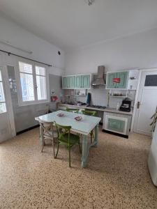 a kitchen with a white table and green chairs at Nomads Hostel Sousse in Sousse