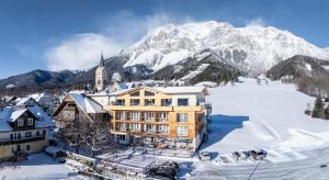 a building in the snow with a mountain in the background at Hotel Pehab - Rooftop-Spa in Ramsau am Dachstein