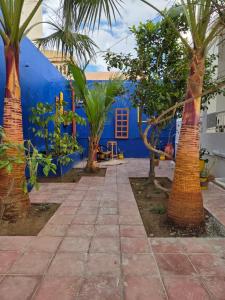 a group of palm trees in front of a blue building at Nomads Hostel Sousse in Sousse