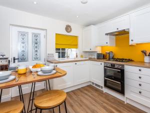 a kitchen with white cabinets and a wooden table at Court Terrace in Ripon