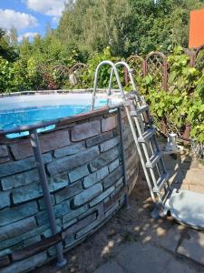 a swimming pool with a ladder next to a brick wall at Sielski Zakątek Tokary in Tokary