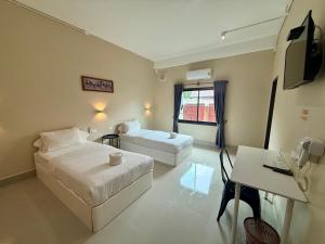 a hotel room with two beds and a desk at Phaythavone Hotel in Pakse
