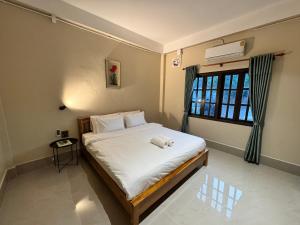 a bedroom with a bed with white sheets and a window at Phaythavone Hotel in Pakse